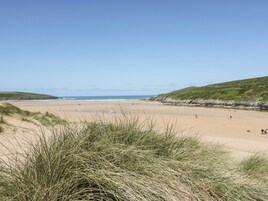 A beach with grassy dunes, a sandy shore, and a clear sky.