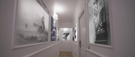 A hallway with framed artwork on the walls and a patterned floor.