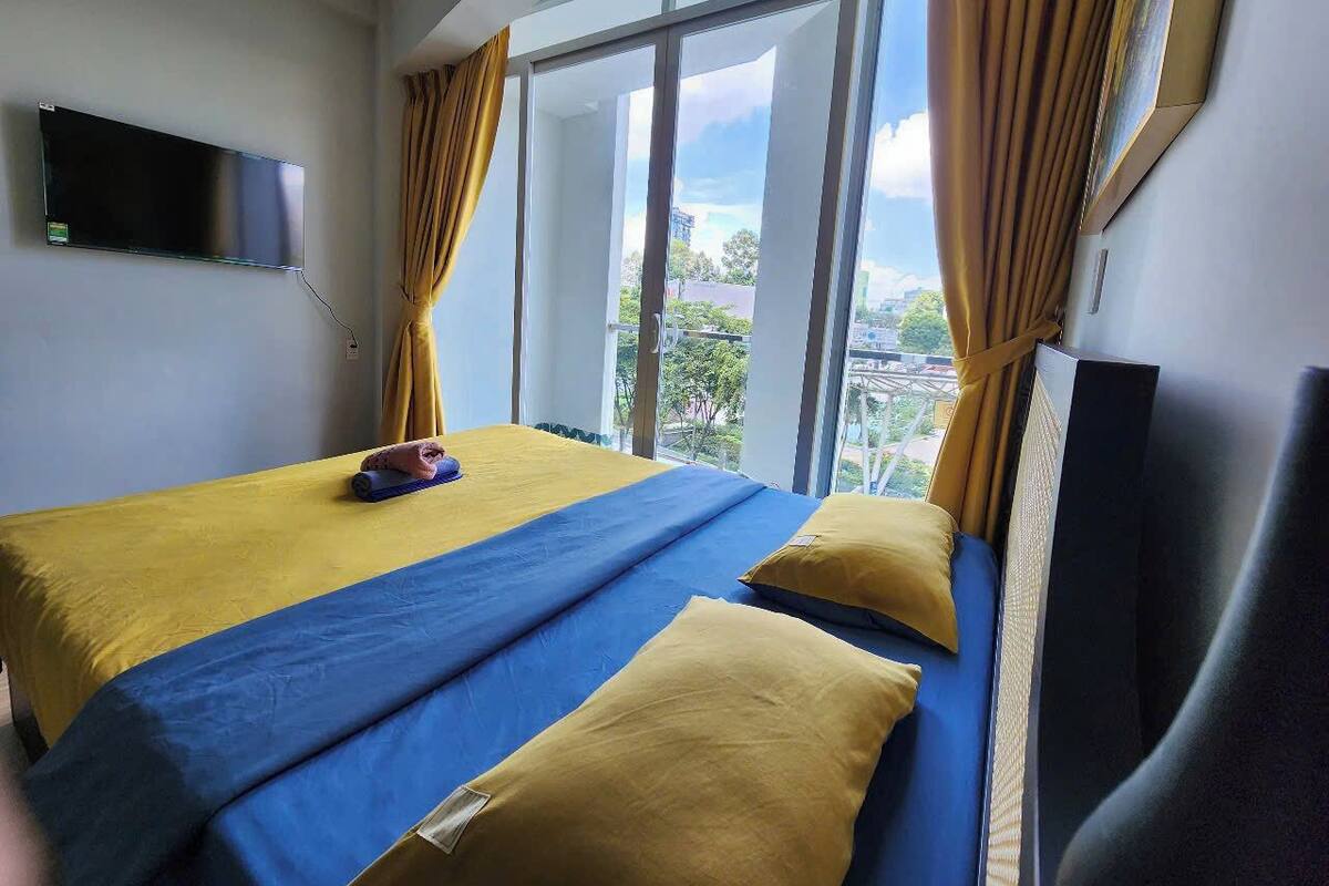 Ein Hotelzimmer mit einem Bett, einem Flachbildfernseher und einem großen Fenster mit Vorhängen.