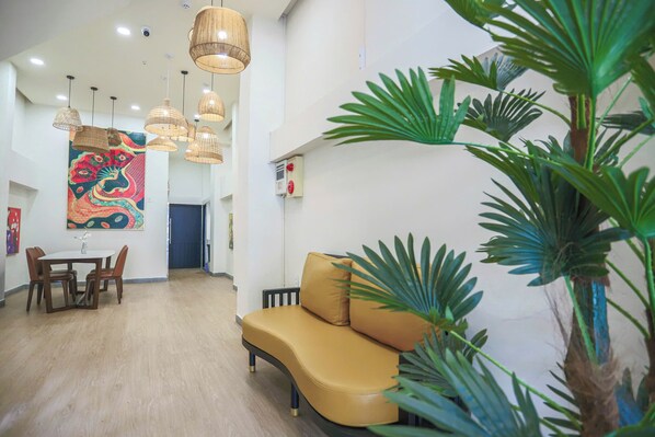 A modern hotel lobby with a dining area, a sofa, and large green plants. - SOHO Suites - BenThanh Market & SG Heart (Ho Chi Minh City)