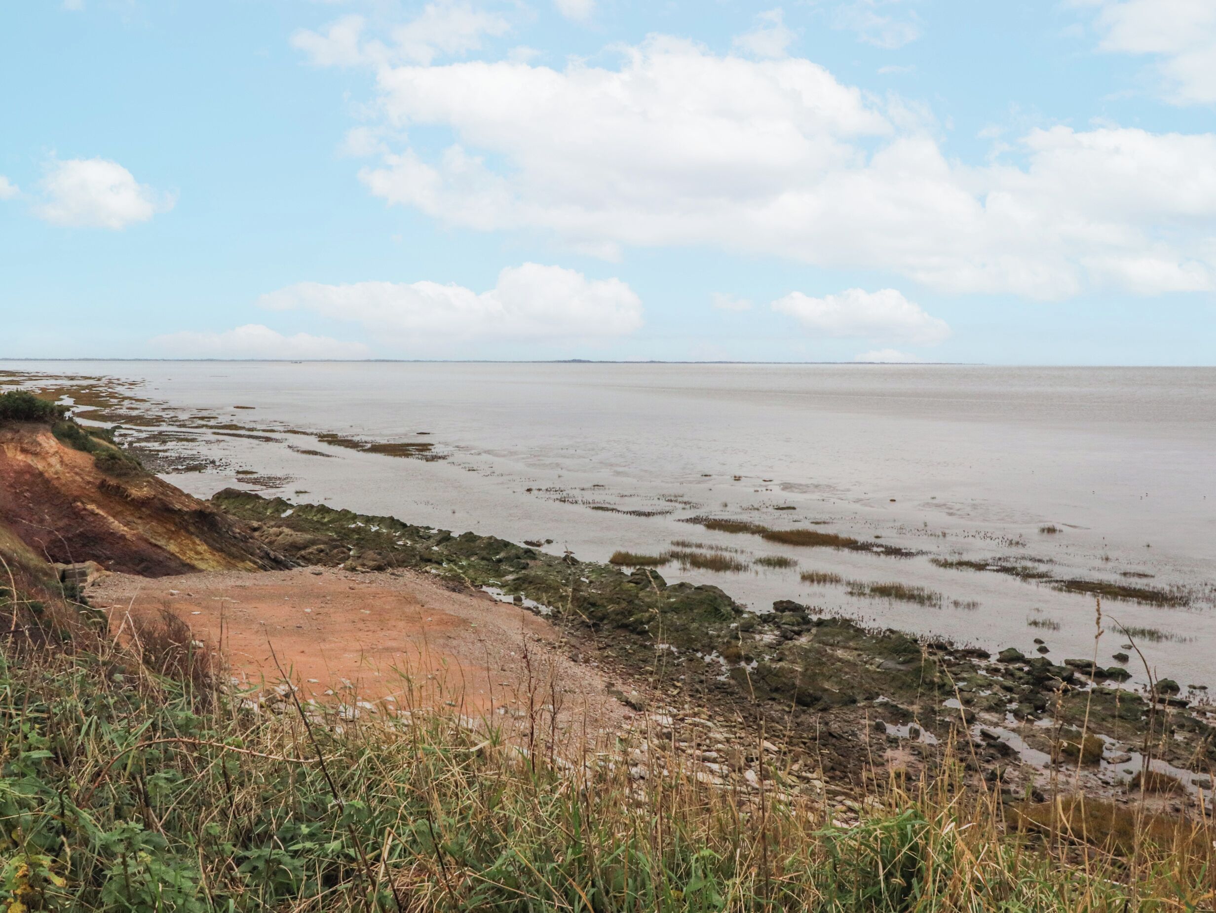 Un paisaje costero con una playa arenosa, un litoral rocoso y vegetación escasa.