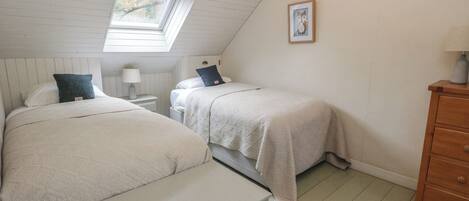 A bedroom with two beds, a window, a nightstand, a dresser, and a framed picture on the wall.