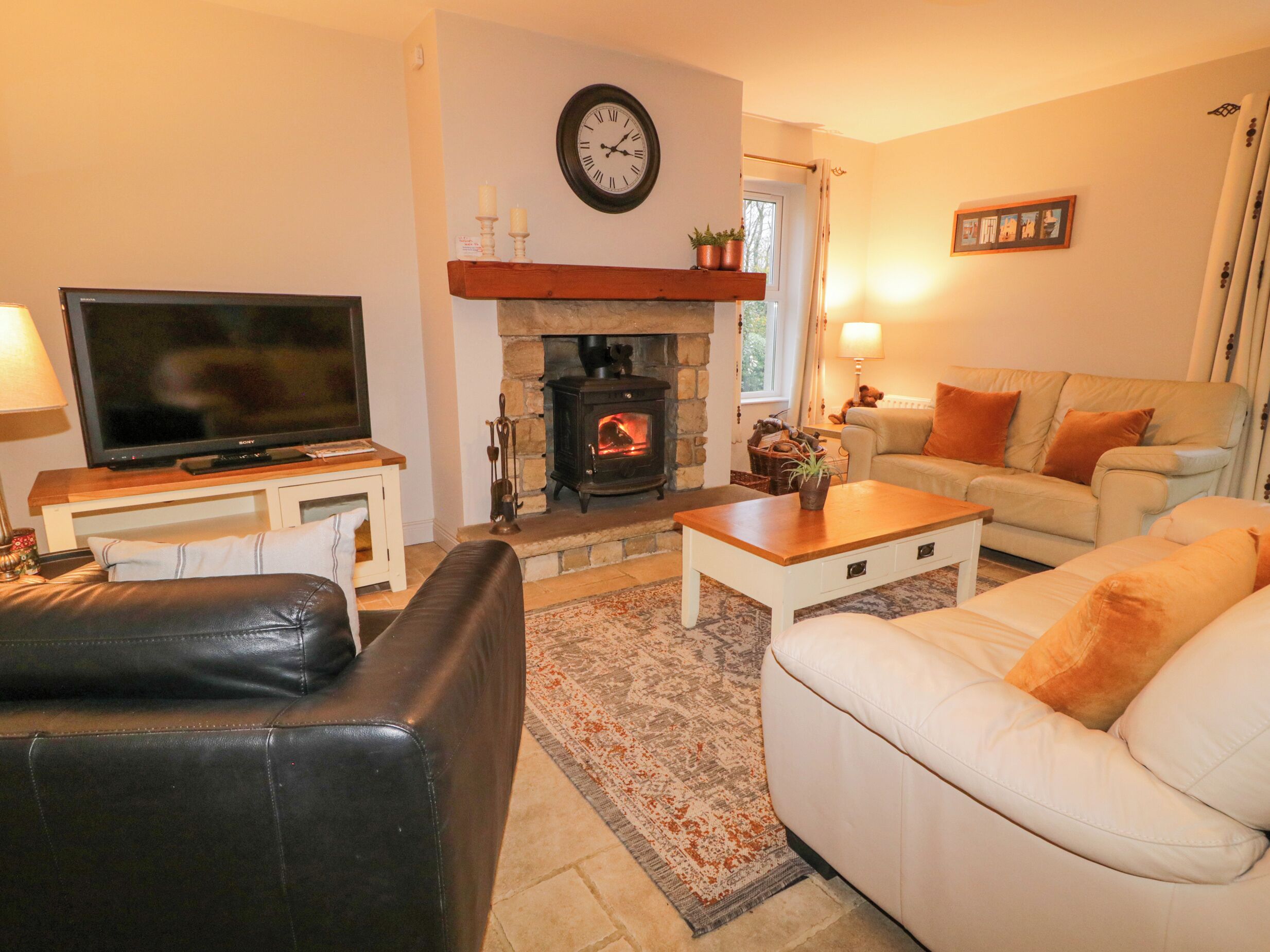 Una sala de estar con chimenea, televisor, sofá y mesa de centro.