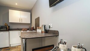 A modern kitchen with white cabinets, a countertop, and a coffee station. - Studio Apartment (Minehead)
