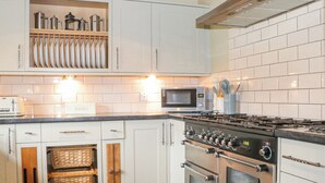 Et moderne køkken med hvide skabe, en stålkogeplade og en mikroovn.