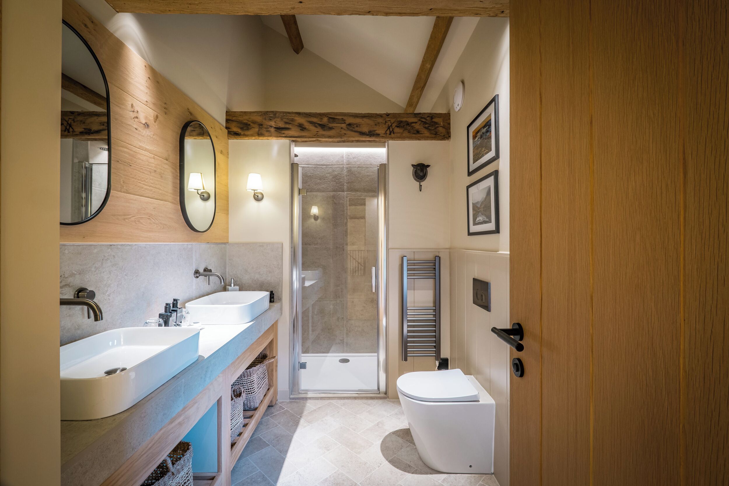 A modern bathroom with two sinks, a shower, and a toilet.