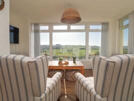 A living room with two striped armchairs facing a large window with a view of a green landscape.