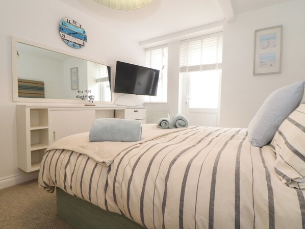 A bedroom with a bed, a TV, a dresser, and a window. - 5 Fistral Waves (Newquay)
