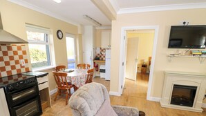 A kitchen with a stove, oven, and dining area with chairs and a table. - Robins Roost 2 (Cornamona)