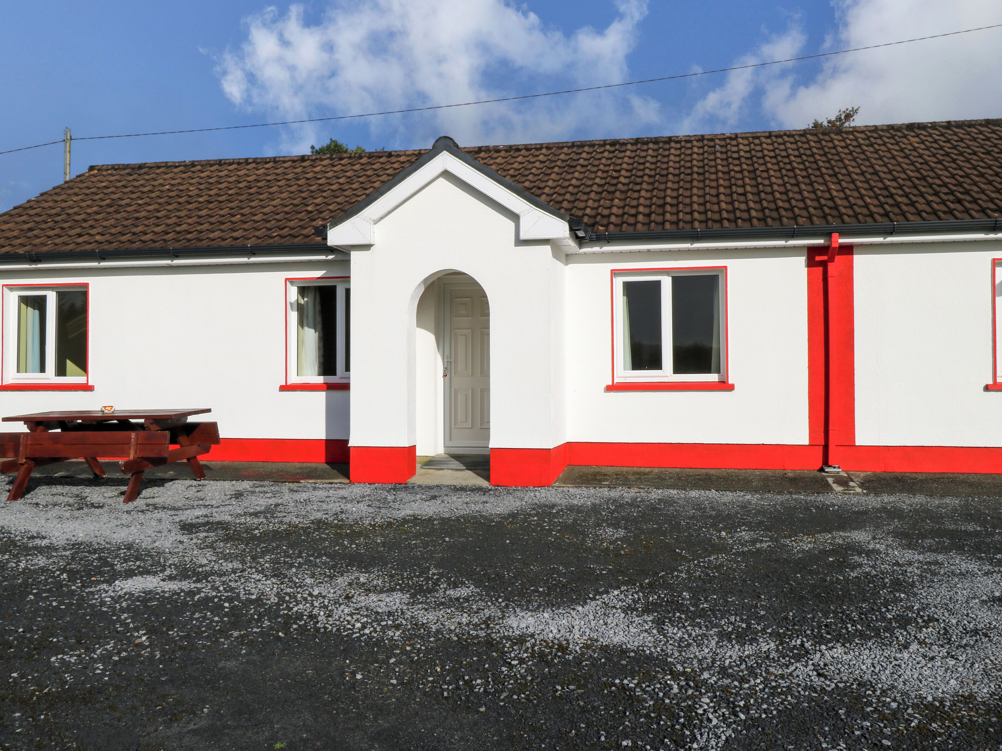 A white building with red trim and a tiled roof.