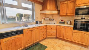 A kitchen with wooden cabinets, a Bosch dishwasher, a Bosch oven, and a window with a view of the outside. - Ritas (Newry)