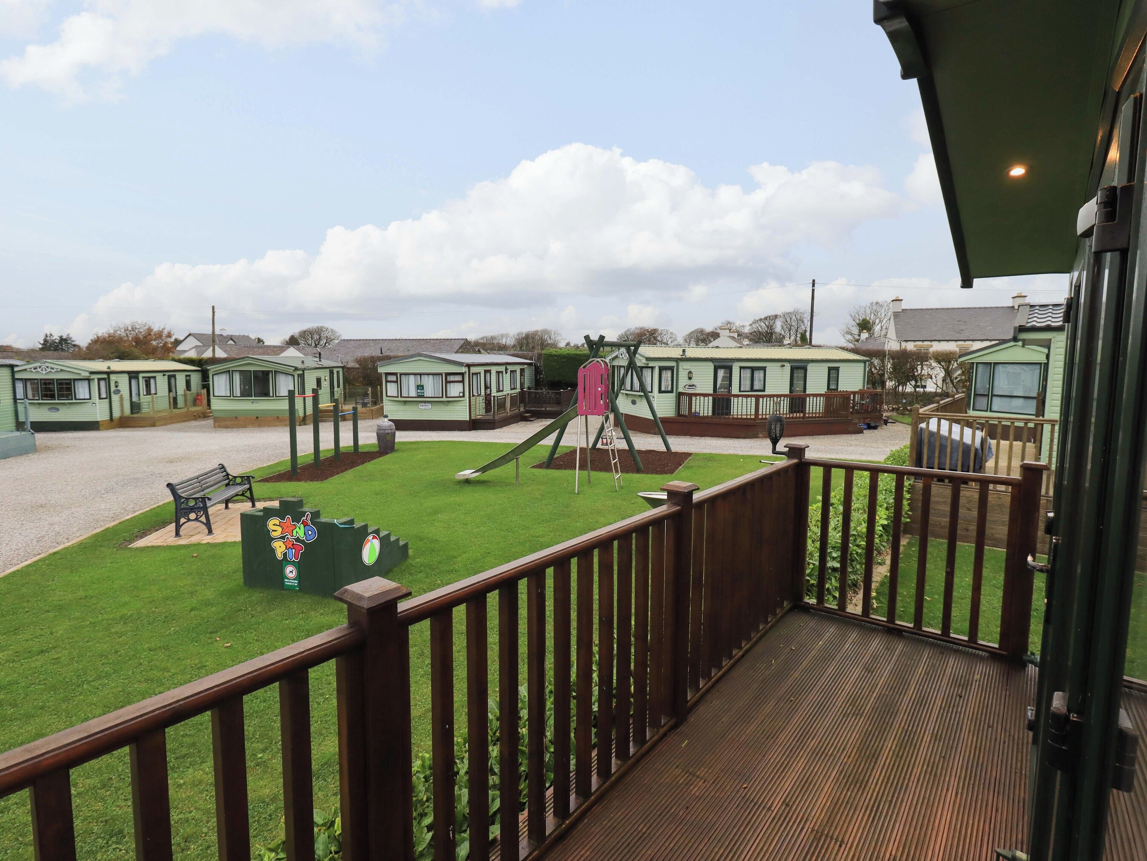 Vista de un parque infantil con tobogán y columpios, rodeado de viviendas móviles con techos verdes.