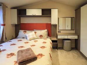 A neatly arranged hotel room with a bed, bedside table, mirror, and a small trash bin. - Highlands Way Lodge (Workington)