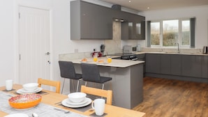 Una cocina moderna con armarios grises, una isla central y un comedor con mesa y sillas de madera.
