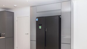 Una cocina compacta con un refrigerador negro, una puerta blanca y gabinetes grises.