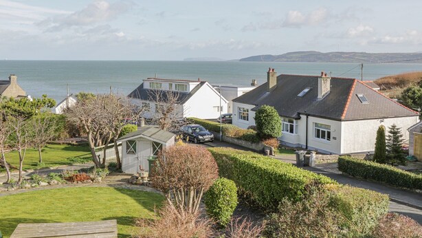 A coastal residential area with houses, a small shed, and a grassy lawn. - Seaview (Tyn-y-Gongl)