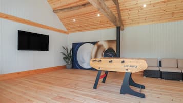 Ein geräumiger Raum mit Holzboden, einem angebrachten Fernseher, einem großen abstrakten Gemälde und einem Stand mit dem Text "HY-PRO".