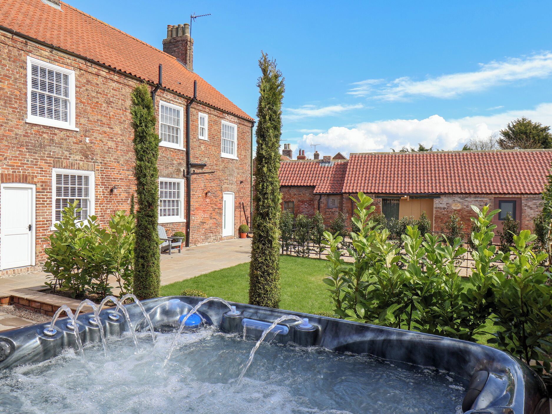A brick house with a garden and a hot tub.