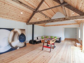 A wooden-floored room with a high ceiling, a sofa with green cushions, and a foosball table. - Harpham Manor House (Driffield)