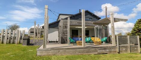 A modern house with a wooden deck and outdoor seating.