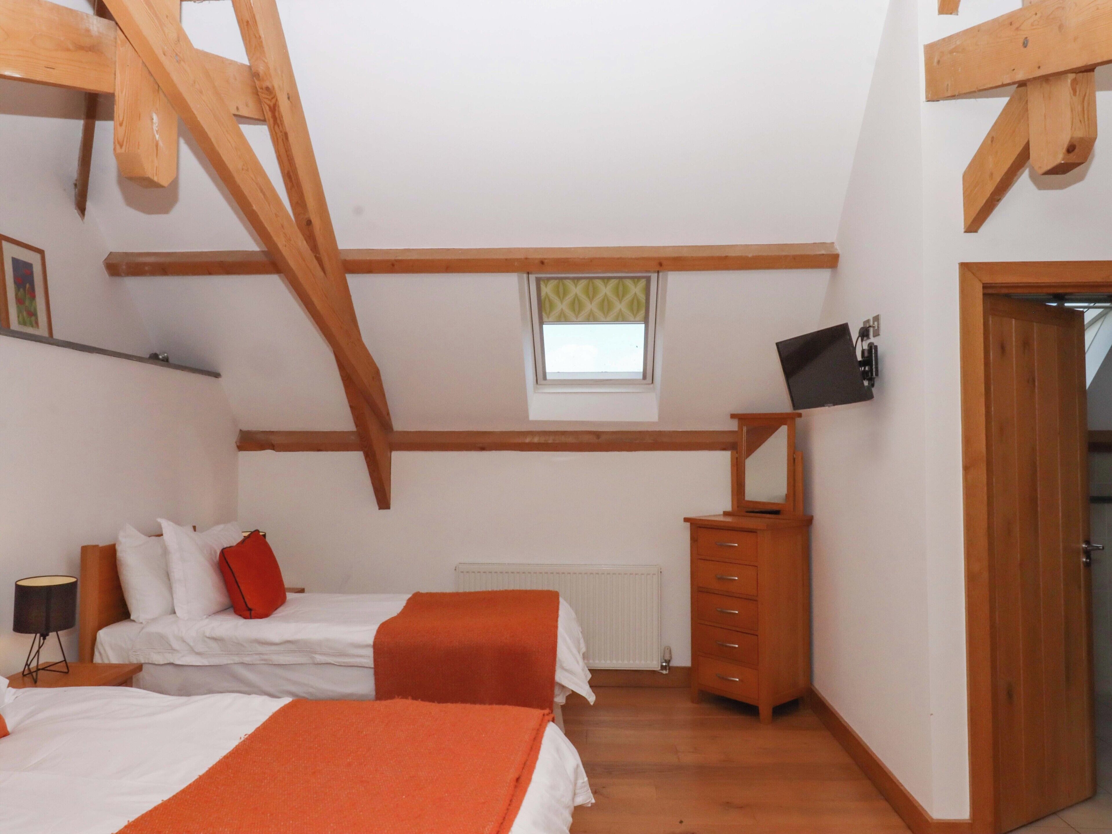 A room with two beds, a dresser, a TV, and a window.