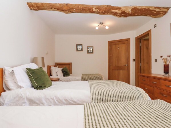 Ein Schlafzimmer mit zwei Betten, Holz-Kopfteilen, einem Schrank aus Holz und einer Deckenleuchte.