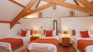 A room with three beds, wooden beams, white walls, and a wooden floor. - Swallows Reach (Totnes)