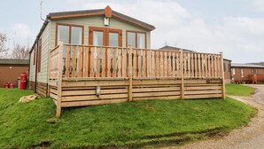 A single-story mobile home with a wooden deck and a fenced backyard. - 6 Sherwood (Carnforth)