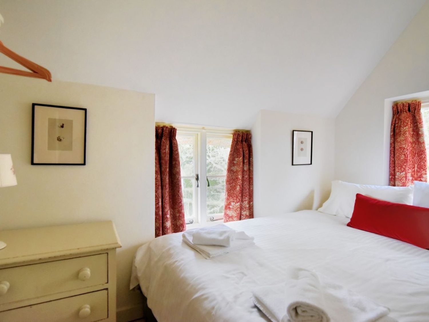 Una camera da letto con un letto, una cassettiera e due quadri appesi al muro.