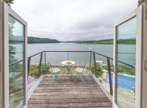 Ein Balkon mit Tisch und Stühlen mit Blick auf einen See.