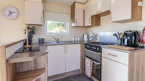 Cocina compacta con un lavamanos, estufa, horno y un reloj en la pared.