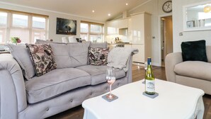 Un salon moderne avec un canapé gris, une table basse blanche et une bouteille de vin.
