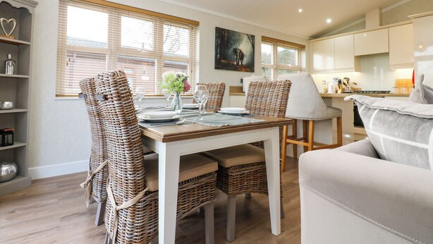 Un coin repas avec des chaises en osier, une table dressée pour quatre personnes et un tableau accroché au mur.