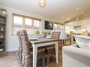 A dining area with wicker chairs, a table set for four, and a painting on the wall. - Finnbars Lodge (Richmond)