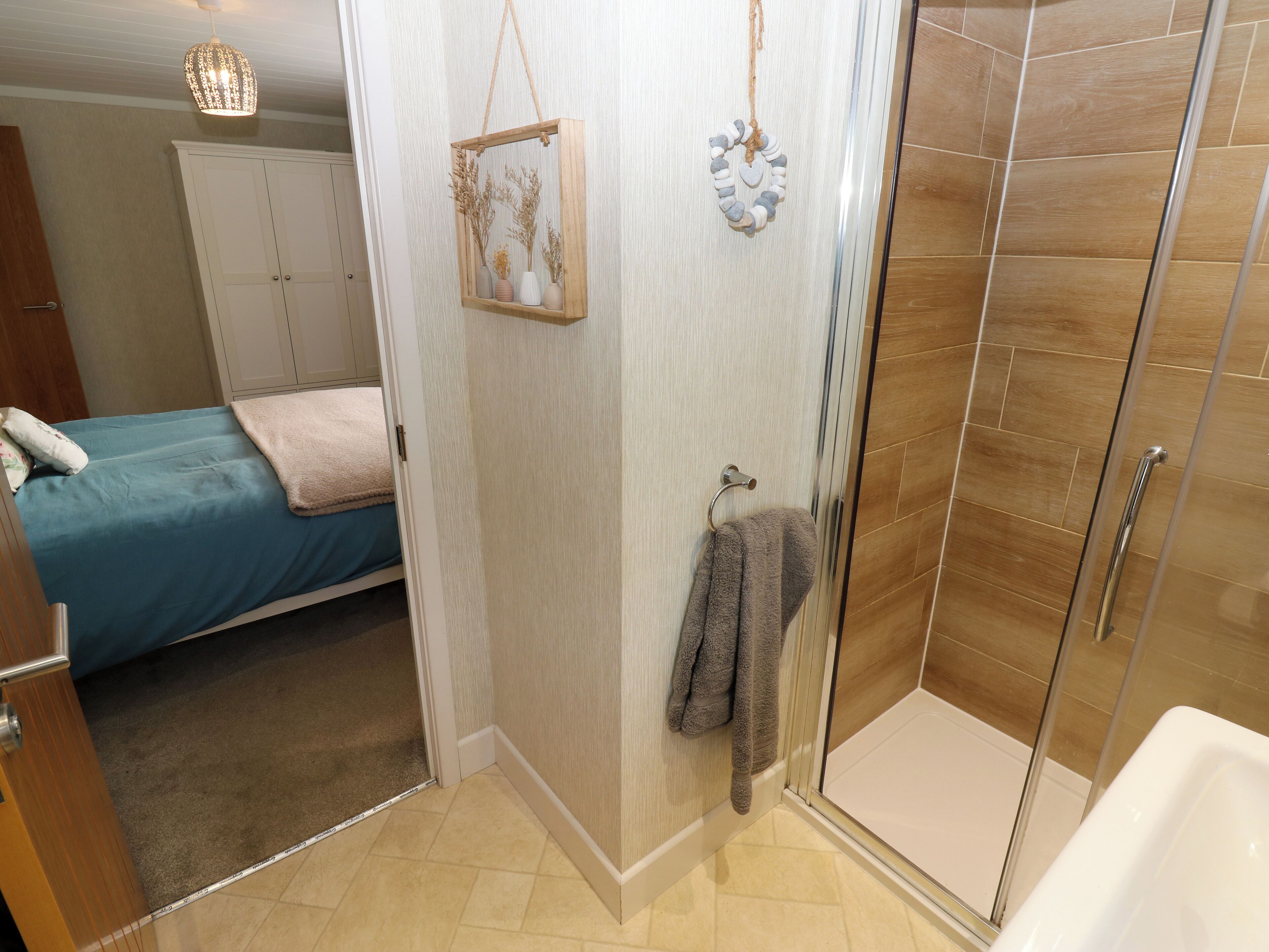 Une salle de bain avec une douche, un porte-serviettes et un lit recouvert d’une couverture bleue.