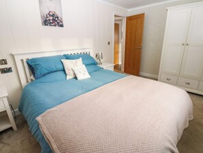Un dormitorio con una cama grande, paredes blancas, una puerta de madera y un armario.