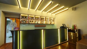 Zona de bar amb barra, estanteries plenes de botelles i un ordinador portàtil.