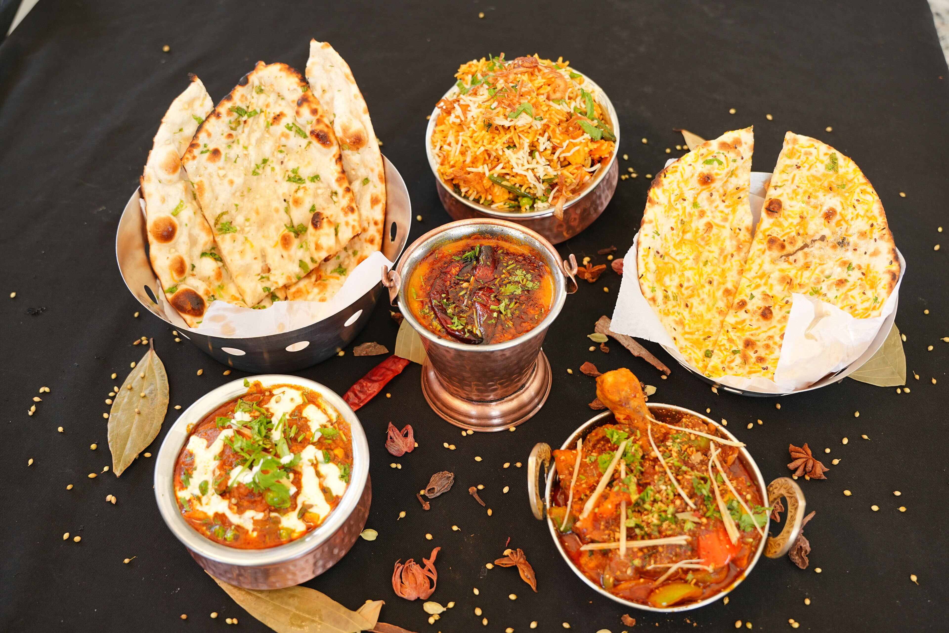 A table with various Indian dishes including naan bread, biryani, and curries.