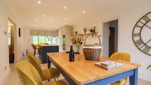 A dining area with a wooden table, yellow chairs, a wicker basket, and a vase with flowers. - The Pines (Skipton)