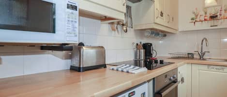 Eine Küche mit weißen Schränken, einer Mikrowelle, einem Toaster, einer Kaffeemaschine und einem Kühlschrank mit Magneten.