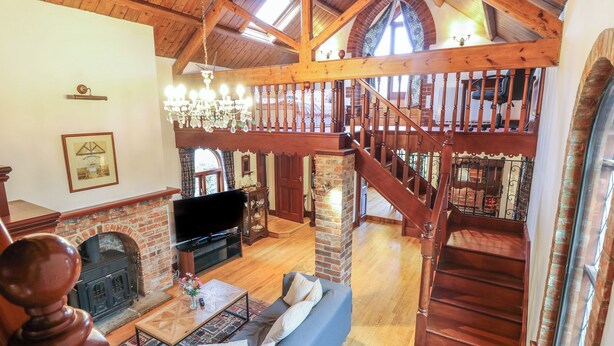 A spacious living room with a fireplace, a large sofa, and a wooden staircase leading to an upper level. - The Chapel (Newport)