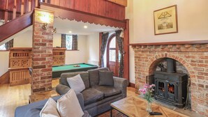 A cozy living room with a sofa, a pool table, a fireplace, and a staircase. - The Chapel (Newport)