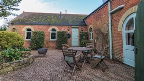 A brick house with a tiled roof, a front door, and a small patio with a table and chairs. - The Chapel (Newport)