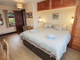 Un dormitorio con una cama grande, un armario de madera y una mesita de noche pequeña.