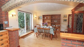 A dining area with a brick fireplace, wooden chairs, a table set with plates and glasses, and a view through a glass door. - The Chapel (Newport)