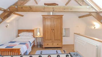 A cozy attic bedroom with a bed, wardrobe, and foosball table.