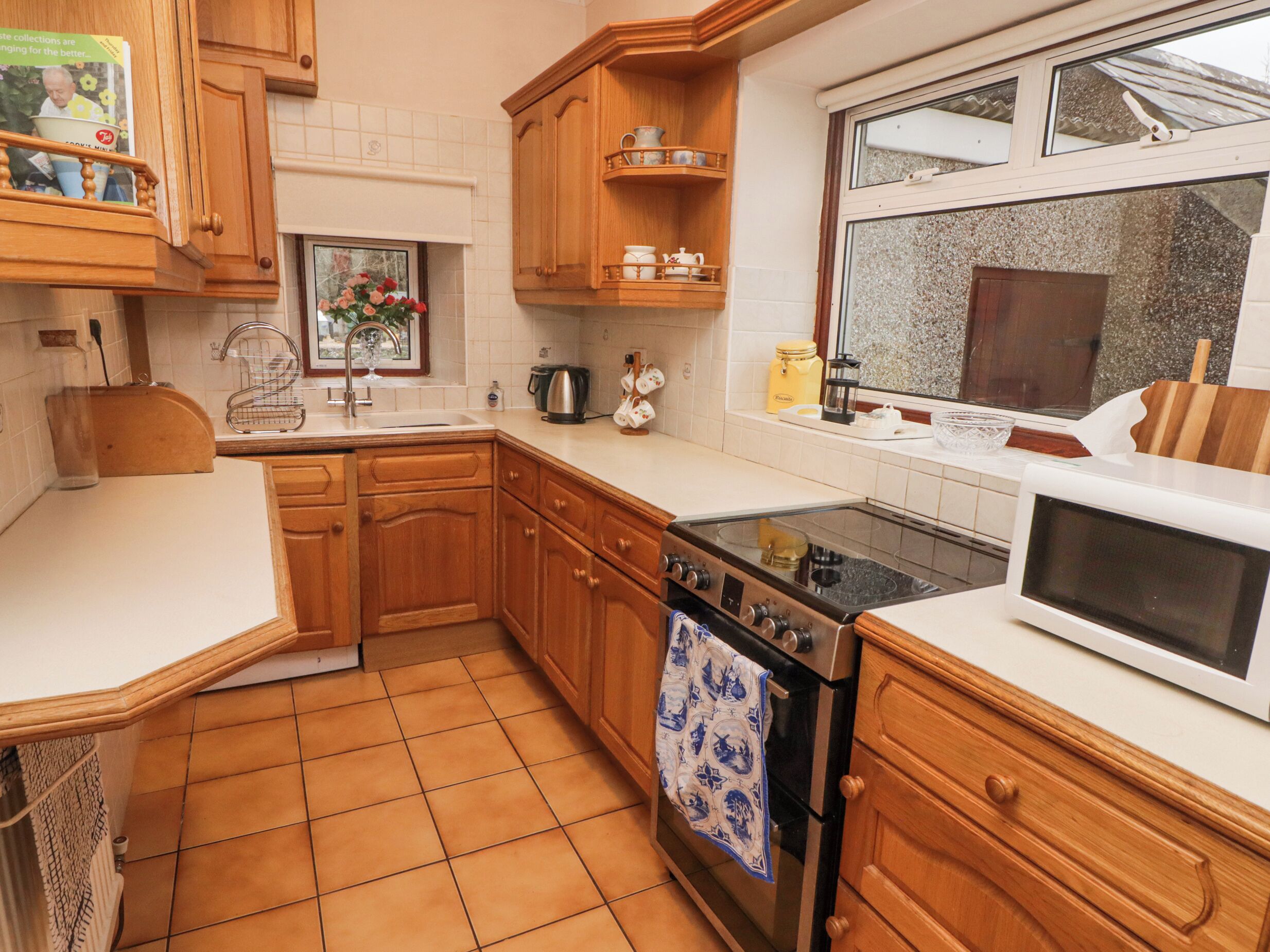 A kitchen with wooden cabinets, a stove, a microwave, and a window with a view.