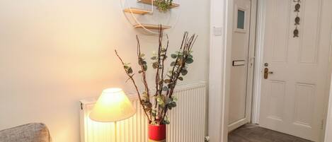 A hallway with a lamp, a red vase with branches, a radiator, and a door labeled "HOME".