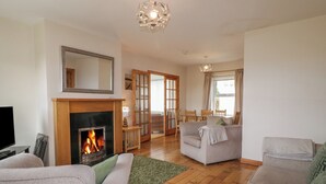 A living room with a fireplace, a television, and a dining area with chairs. - Horn Head View (Carrigart)