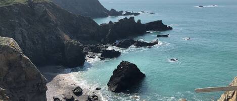 A coastal landscape with rocky cliffs and a clear view of the sea.